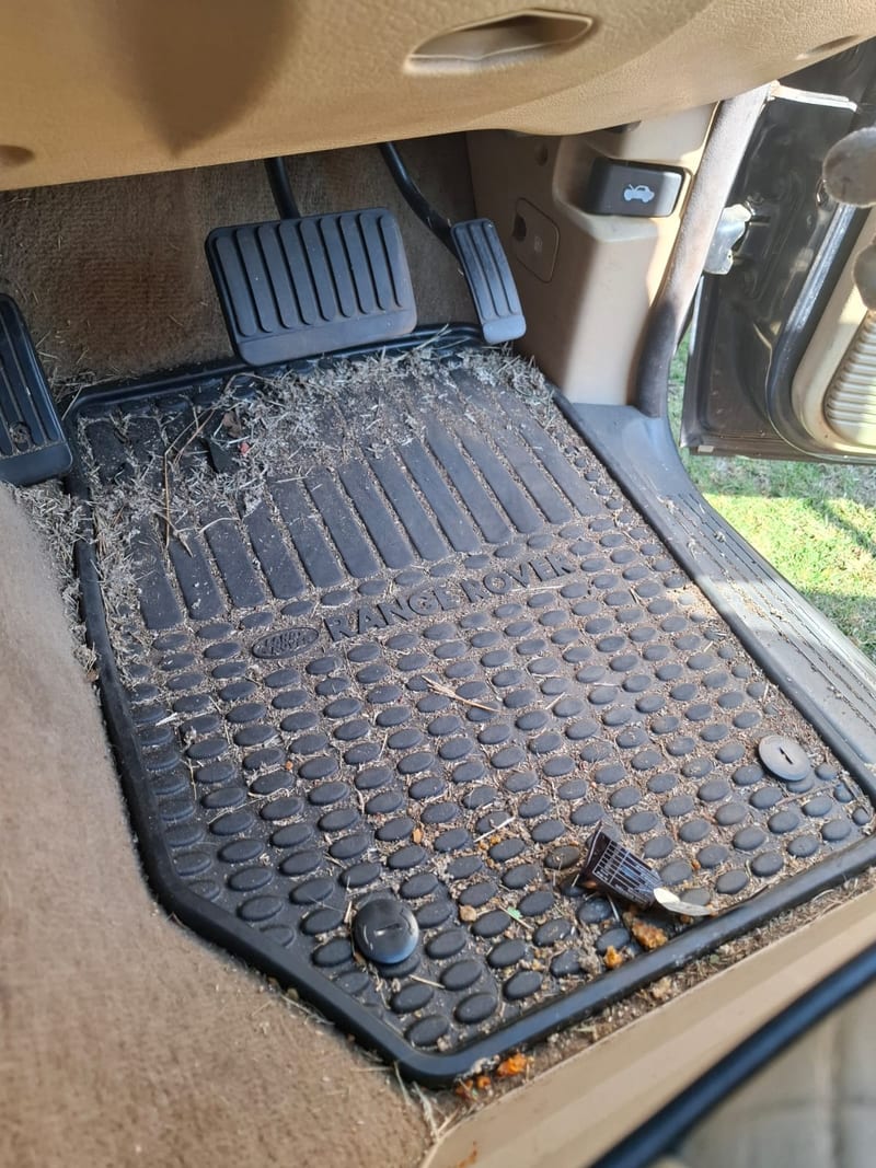 Range Rover driver footwell before detailing — rubber mat caked in dust and debris, Johannesburg North
